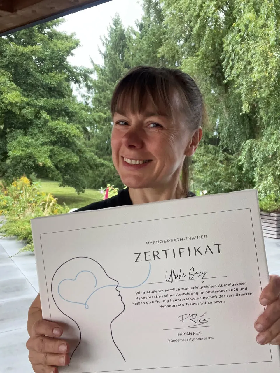 Ulrike hält ihr Hypnobreath®-Trainer-Zertifikat in die Kamera
