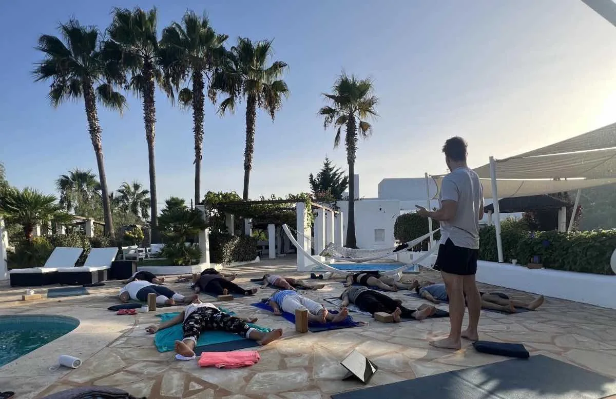 Fabian Ries leitet eine Hypnobreath®-Session am Pool, die Gruppe liegt auf Matten