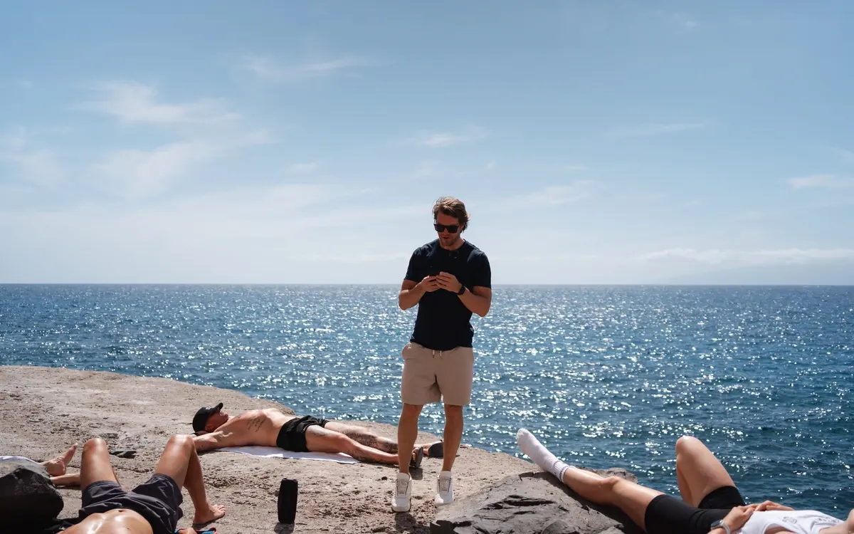 Gruppensession am Meer: Athleten liegen auf den Felsen, Fabian leitet an