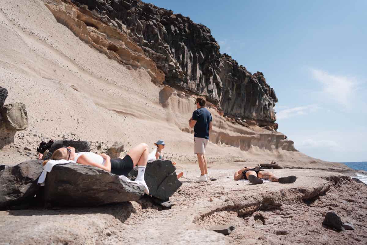Teilnehmer liegen auf Felsen am Meer, Fabian Ries leitet die Session